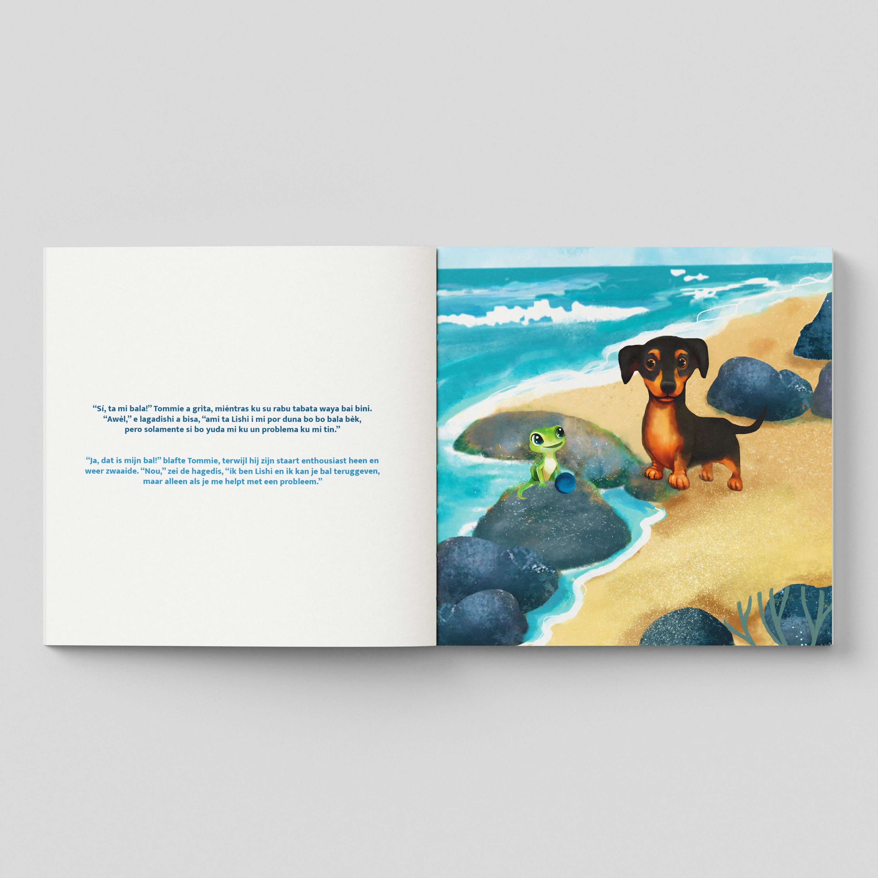 Inhoud van het paperback boek met de titel "Aventuranan di Tommie i Lishi - De avonturen van Tommie en Lishi". De linkerpagina bevat de tekst in zowel Papiamentu als Nederlands over een gesprek tussen Tommie de Jack Russell en de hagedis Lishi. De rechterpagina toont een vrolijke illustratie van een bruin-zwart hondje (Tommie) en een groene hagedis (Lishi) die op donkere rotsen staan aan een zonnig strand met helderblauw water.