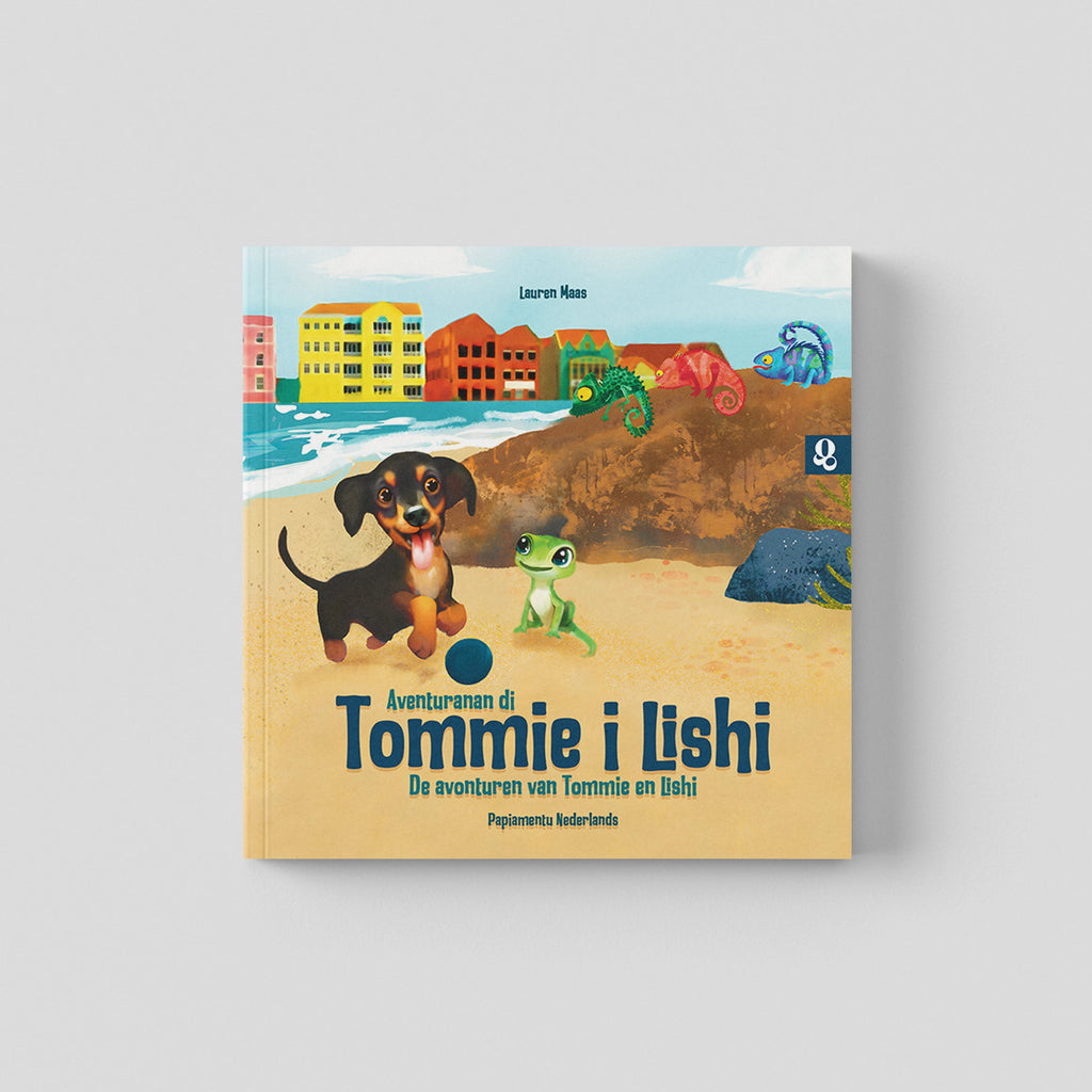Omslag van een paperback boek met de titel "Aventuranan di Tommie i Lishi - De avonturen van Tommie en Lishi". De illustratie toont een zwarte Jack Russell (Tommie) en een kleine groene hagedis (Lishi) op een zandstrand. Op de achtergrond staan gekleurde huizen zoals in Curaçao, zijn er golven van de zee en zitten er drie kleurrijke leguanen op een heuvel.